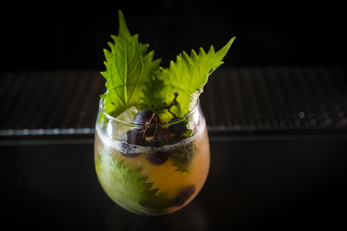 A  cocktail garnished with kyoho grapes and shiso leaves