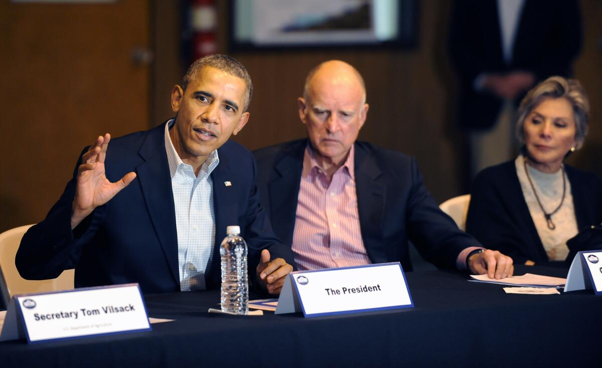 President Obama and Gov. Jerry Brown, seen in a 2014 drought meeting, remain popular figures in California, according to a new poll. But Californians are concerned about the economy and politics.