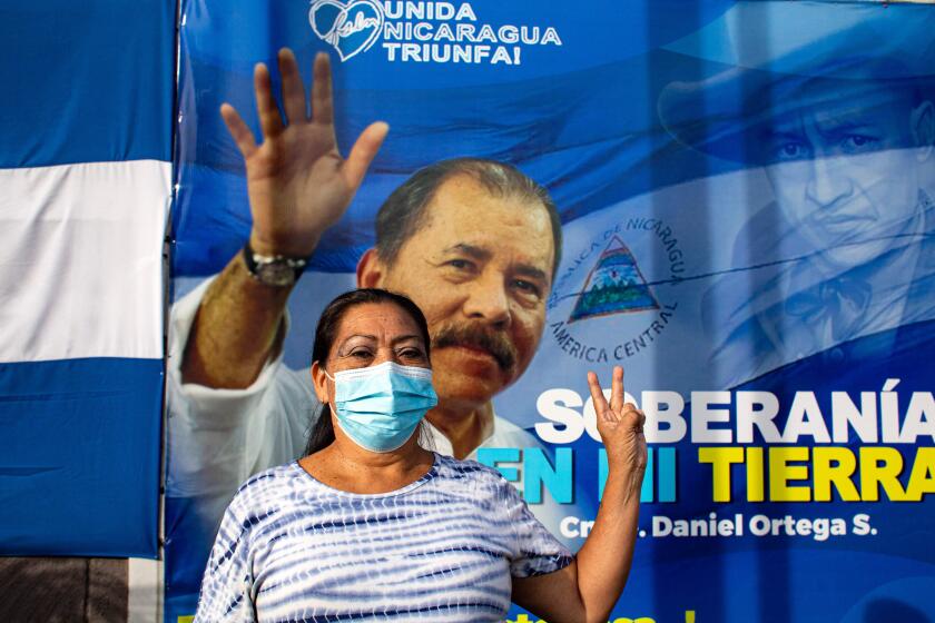 A woman gestures in front of a banner promoting Nicaragua's President Daniel Ortega candidacy in Managua on September 24, 2021. - Nicaragua officially kicks off campaigning for the 7 November presidential elections on Saturday, with President Daniel Ortega's main rivals arrested and the way clear for him to seek a fourth consecutive term in office. (Photo by OSWALDO RIVAS / AFP) (Photo by OSWALDO RIVAS/AFP via Getty Images)