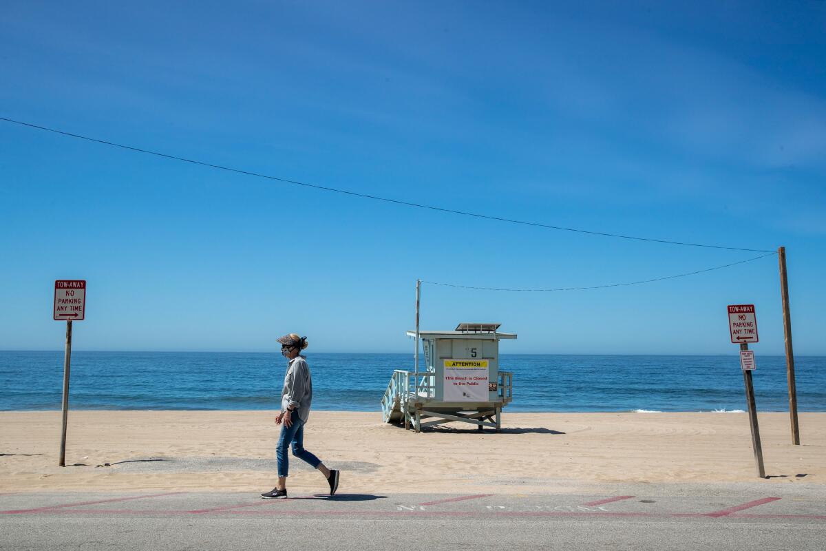 A person walks along a beachfront road and past a lifeguard tower.