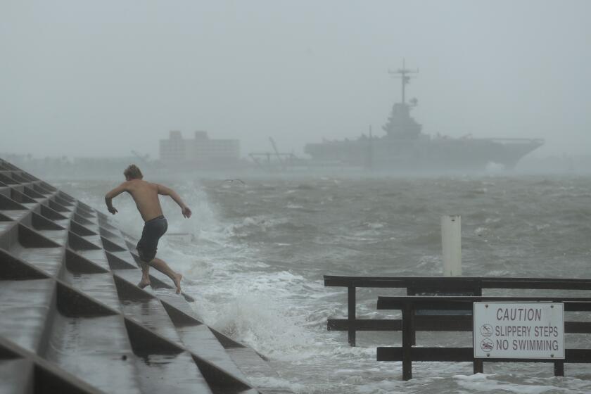 A man jumps from a wave as Hurricane Hanna begins to make landfall, Saturday, July 25, 2020, in Corpus Christi, Texas. The National Hurricane Center said Saturday morning that Hanna's maximum sustained winds had increased and that it was expected to make landfall Saturday afternoon or early evening.(AP Photo/Eric Gay)