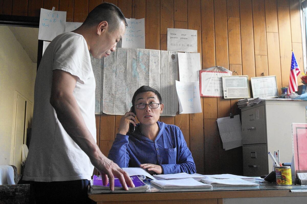 Steve Wang, left, speaks with Genxing Qin at Xing Xing Employment Agency in Monterey Park. Xing Xing is one of at least a dozen employment agencies near Garfield and Garvey avenues.