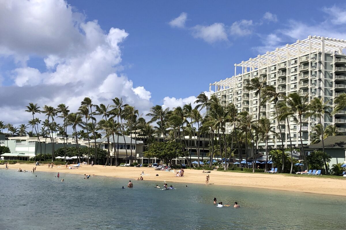 People hang out on the beach and play in the water in front of the Kahala Hotel & Resort in Honolulu. 