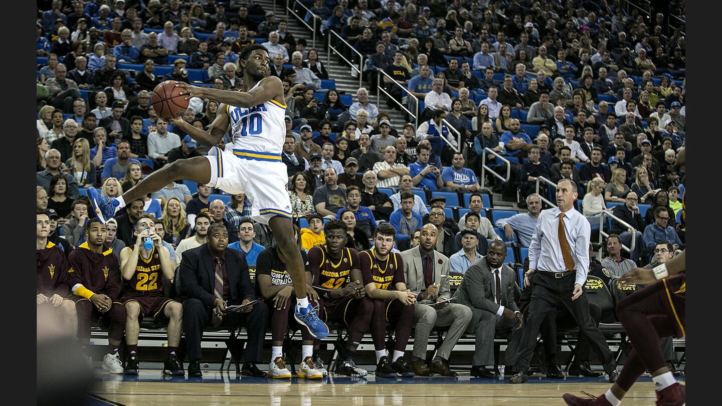 UCLA guard Isaac Hamilton leaps to save a loose ball in front of the ASU bench and Coach Bobby Hurley during the first half