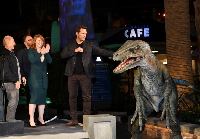 Chris Pratt (der.) establece contacto con una de las figuras de dinosarios en el parque temático.