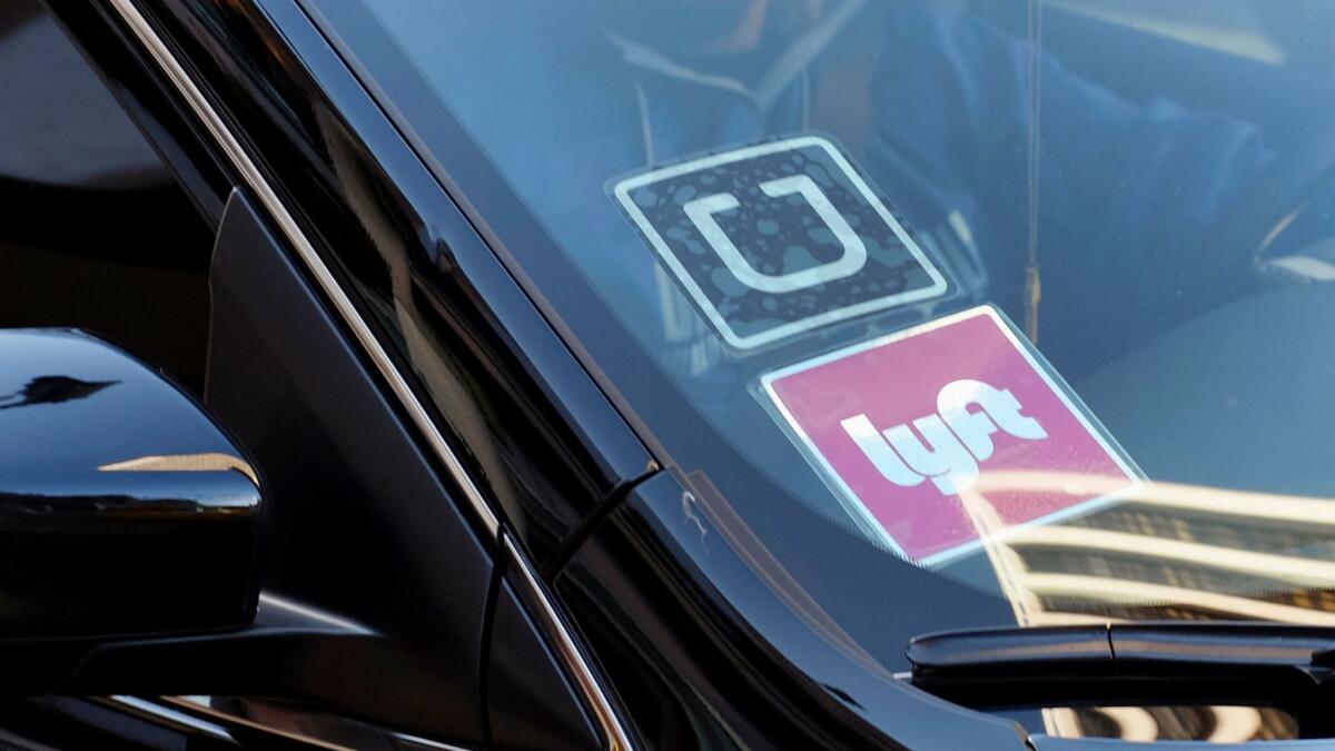 A driver displaying Lyft and Uber stickers on his windshield drops off a customer in downtown Los Angeles on Jan. 12, 2016.