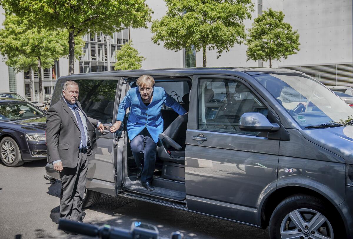 Chancellor Angela Merkel arrives for a legislative session at the Reichstag building in Berlin. To maintain social distancing, she is chauffered by minivan.