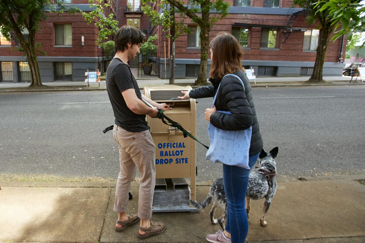 People put their ballots for Oregon's primary election into the collection box in Portland, Ore., on Tuesday.