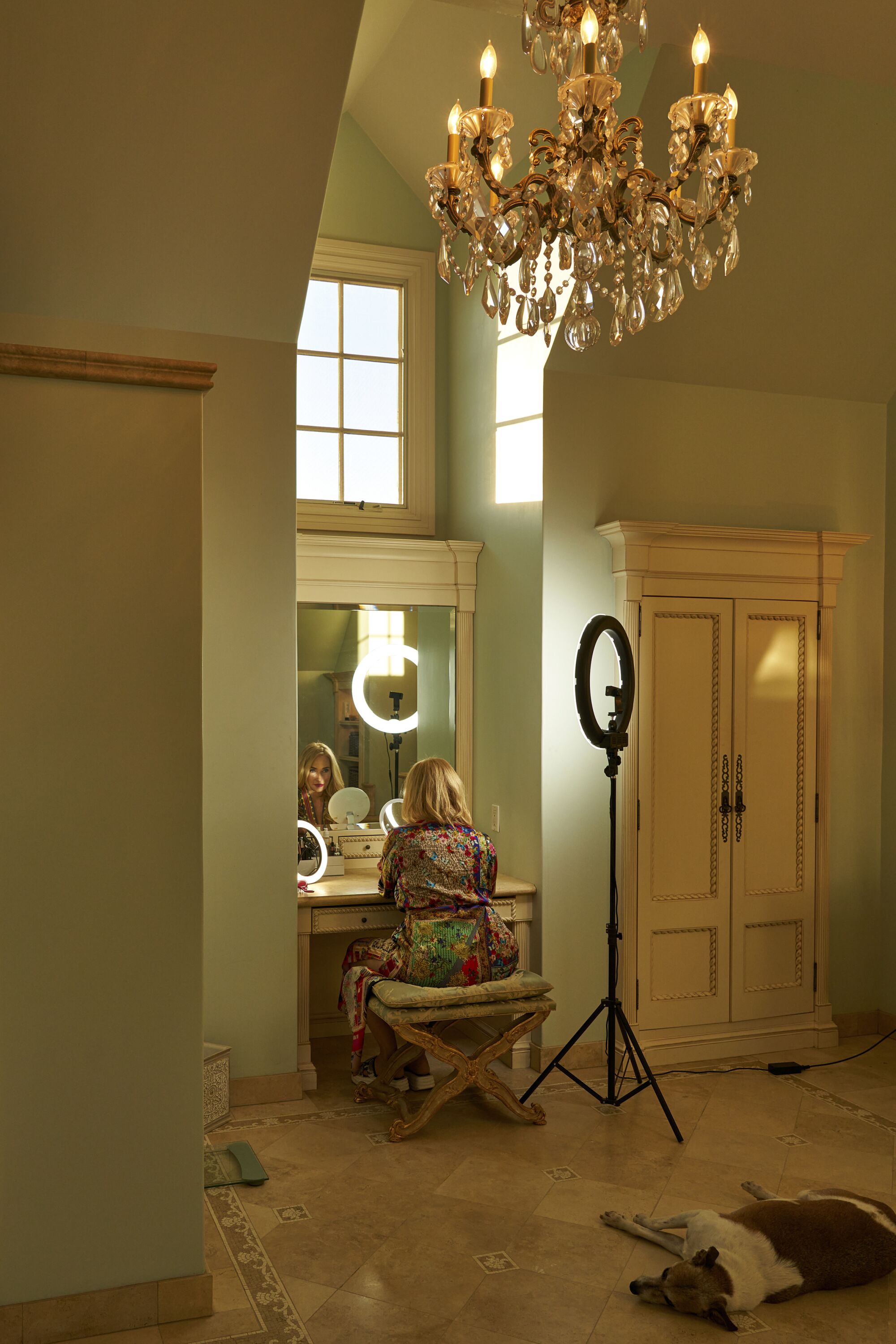A woman applies makeup in a mirror in a bathroom.