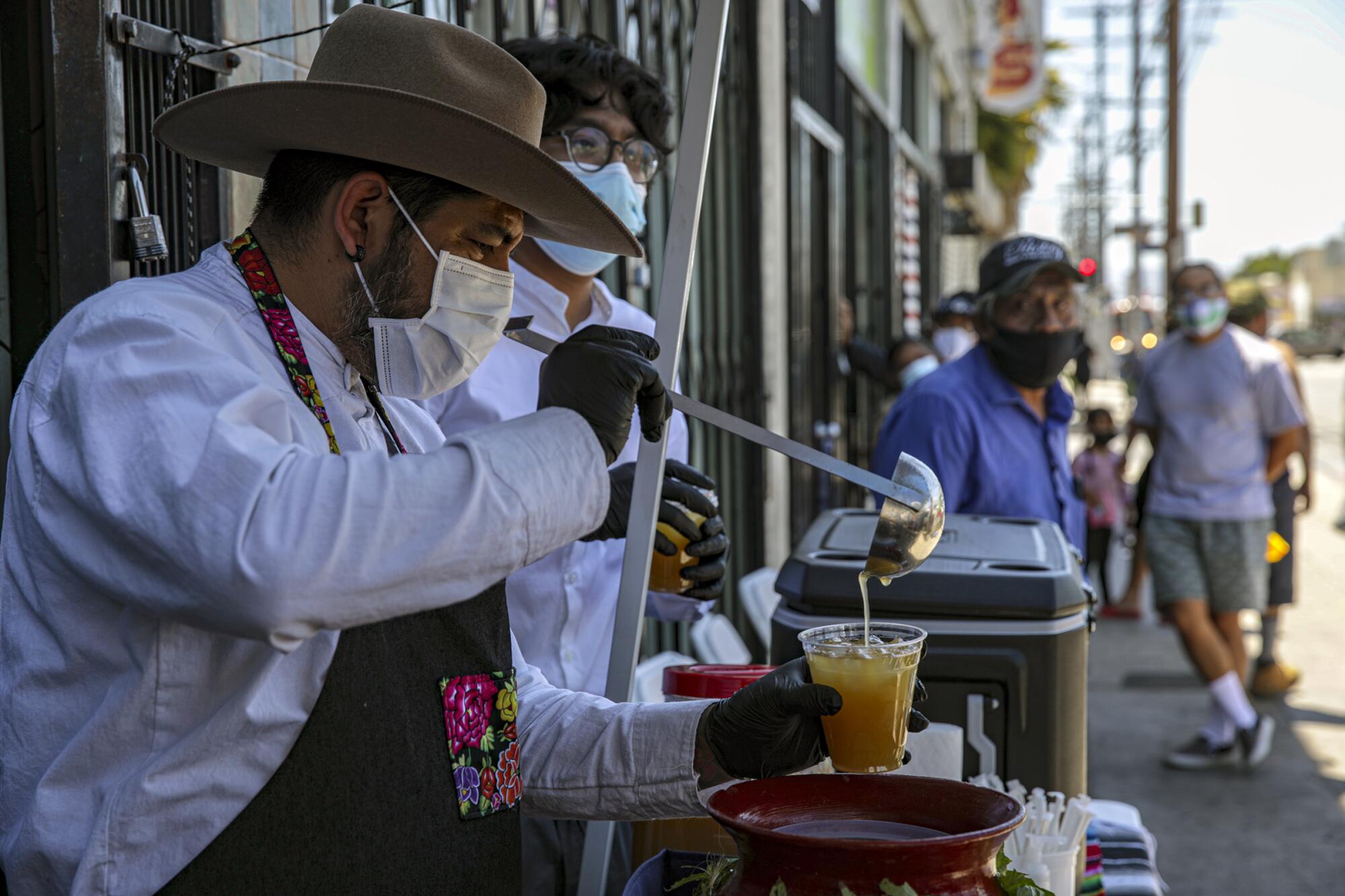 A man pours a drink into a cup to hand out outside