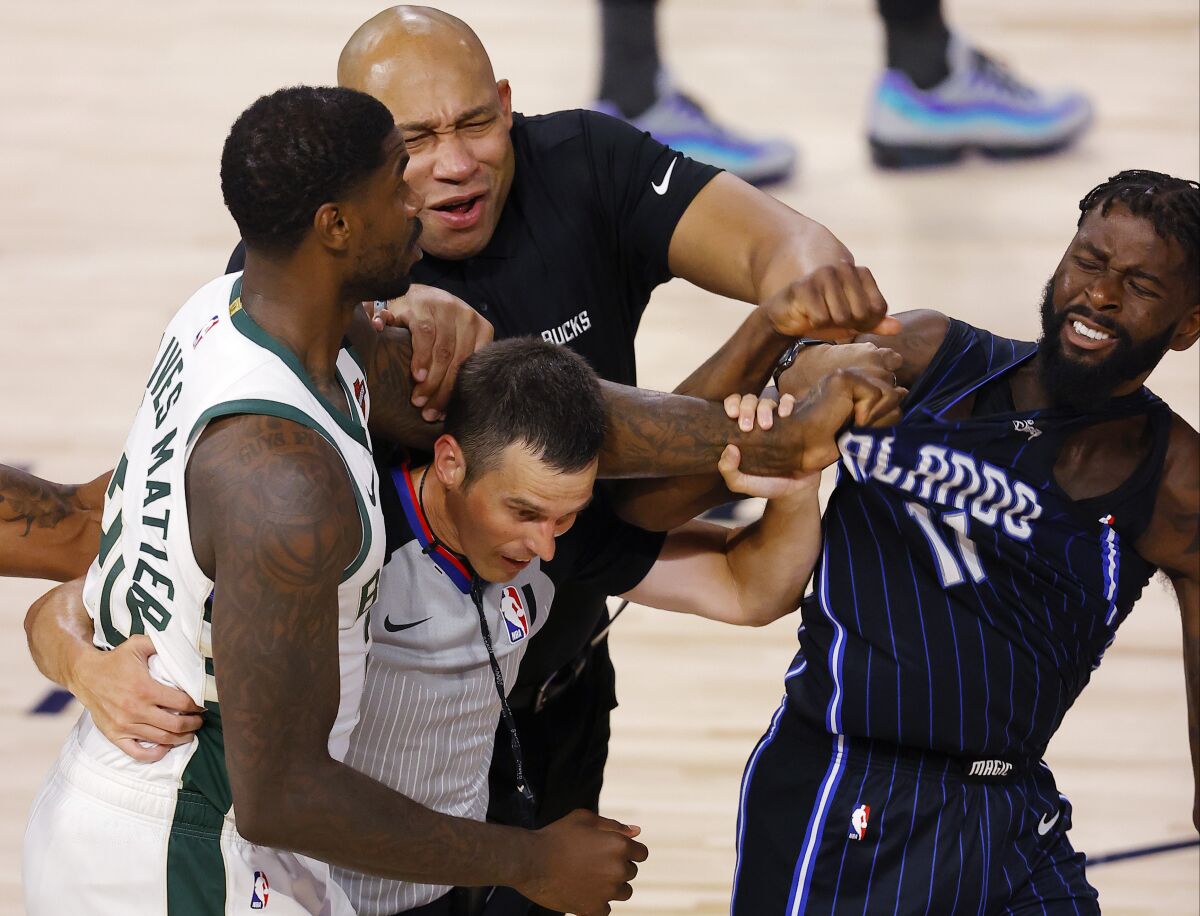 Bucks forward Marvin Williams (20) grabs Magic forward James Ennis III (11) as officials try to separate them during Game 3.