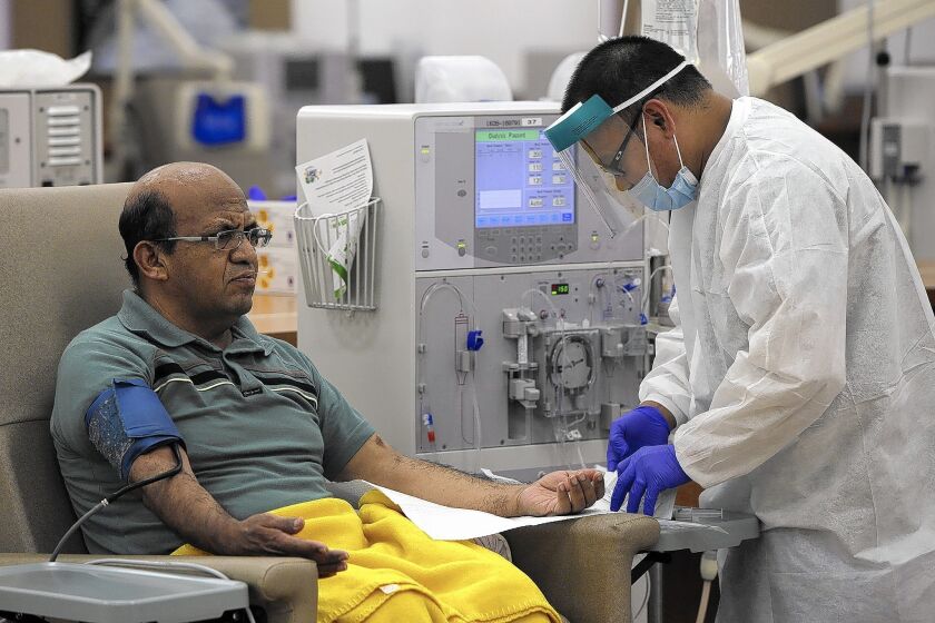 Giraldo Garcia left, is helped by technician Leodegario Ventura at DaVita Dialysis Center in Inglewood. Patients like Garcia who are treated at dialysis centers are not affected by a shortage of home dialysis solution.