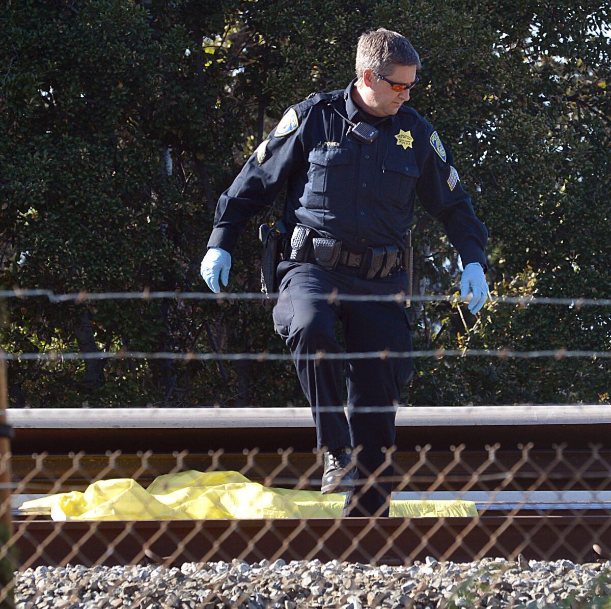 A BART police officer looks along the BART tracks along Jones Road in Walnut Creek, where a moving train struck and killed two workers on Oct. 19, 2013.