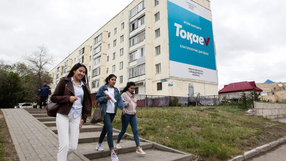 Young women walk past an election campaign billboard for Kazakh president and presidential candidate Kassym-Jomart Tokayev in Nur-Sultan on June 5, 2019, ahead of Kazakhstan's presidential elections on June 9.