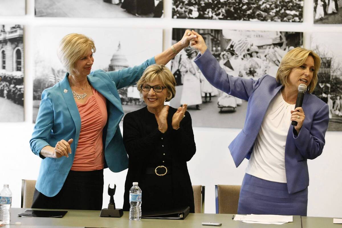 U.S. Rep. Janice Hahn, left, holds up the hand of L.A. mayoral candidate Wendy Greuel as Sen. Barbara Boxer claps at a meeting of The Feminist Majority in Beverly Hills.