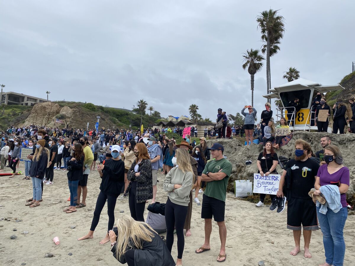 Demonstrators supporting the Black Lives Matter movement watch as surfers paddle out June 6 at Tourmaline Surfing Park.