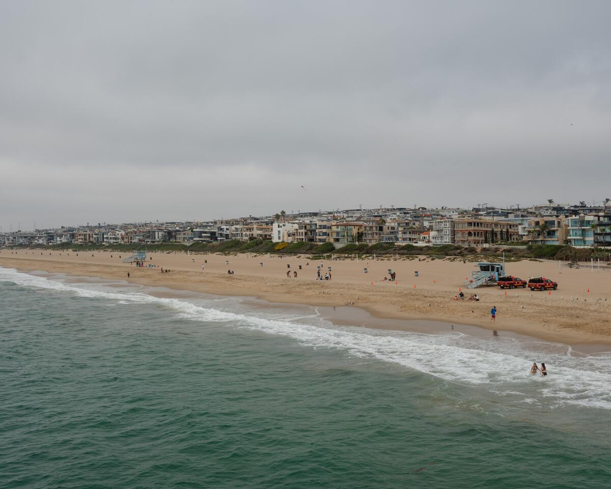 Manhattan Beach shoreline with people on the beach and buildings in the distance.