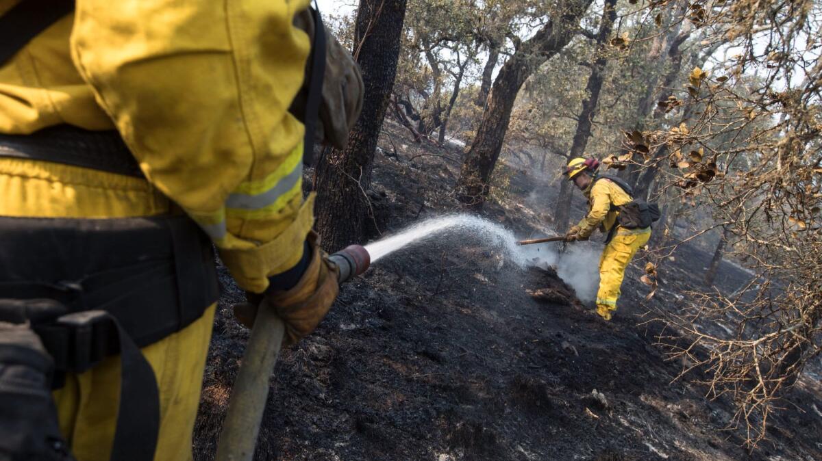 Cal Fire firefighters Tino Loconte, right, and Jon Flinn hit hot spots left by the Tubbs fire along Petrified Forest Road near Calistoga,