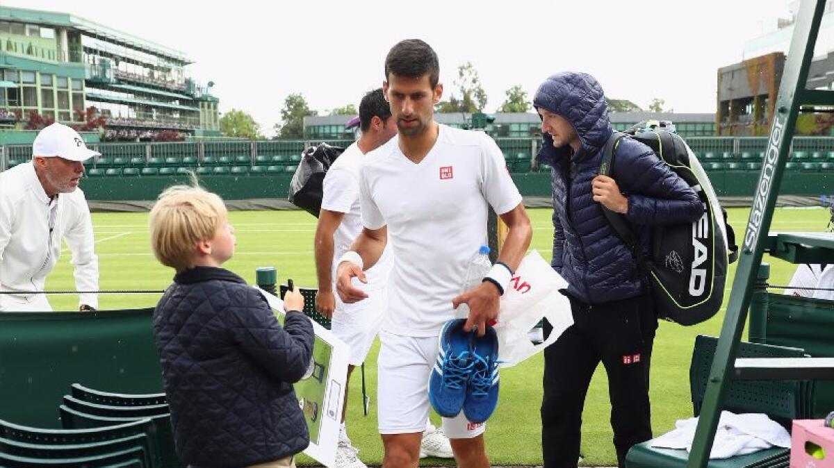 Novak Djokovic of Serbia leaves the court as rain begins to fall during a practice ahead of the 2016 Wimbledon Championships.