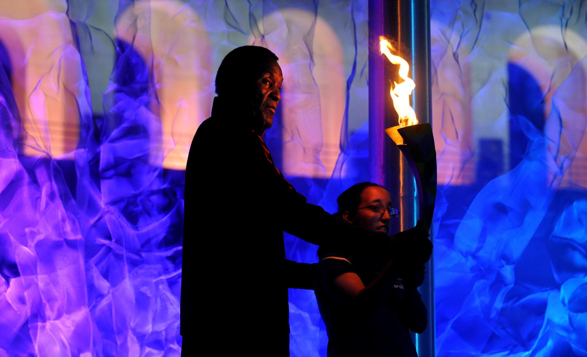 Rafer Johnson holds the torch after lighting the cauldron during the opening ceremony for the World Games at the Coliseum.