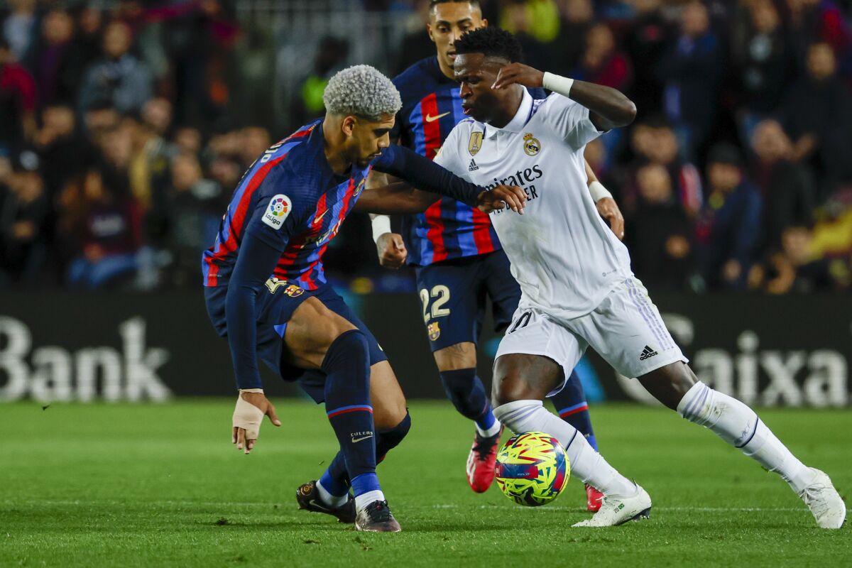 FILE - Real Madrid's Vinicius Junior, right, and Barcelona's Ronald Araujo fight for the ball during Spanish La Liga soccer match between Barcelona and Real Madrid at the Camp Nou stadium in Barcelona, Spain, Sunday, March 19, 2023. The Spanish league said Thursday, March 23, 2023, that it has filed a complaint to judicial authorities for the racist insults that Real Madrid player Vinícius Júnior suffered from rival fans during last week’s Spanish league game at Barcelona. (AP Photo/Joan Monfort, File)