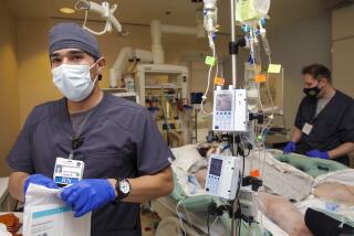Colton, CA - January 11: Newly hired registered nurse Ricardo Miranda, left, works under the supervision of a registered nurse preceptor Brian Stevenson in COVID ICU at Arrowhead Regional Medical Center on Tuesday, Jan. 11, 2022 in Colton, CA. (Irfan Khan / Los Angeles Times)