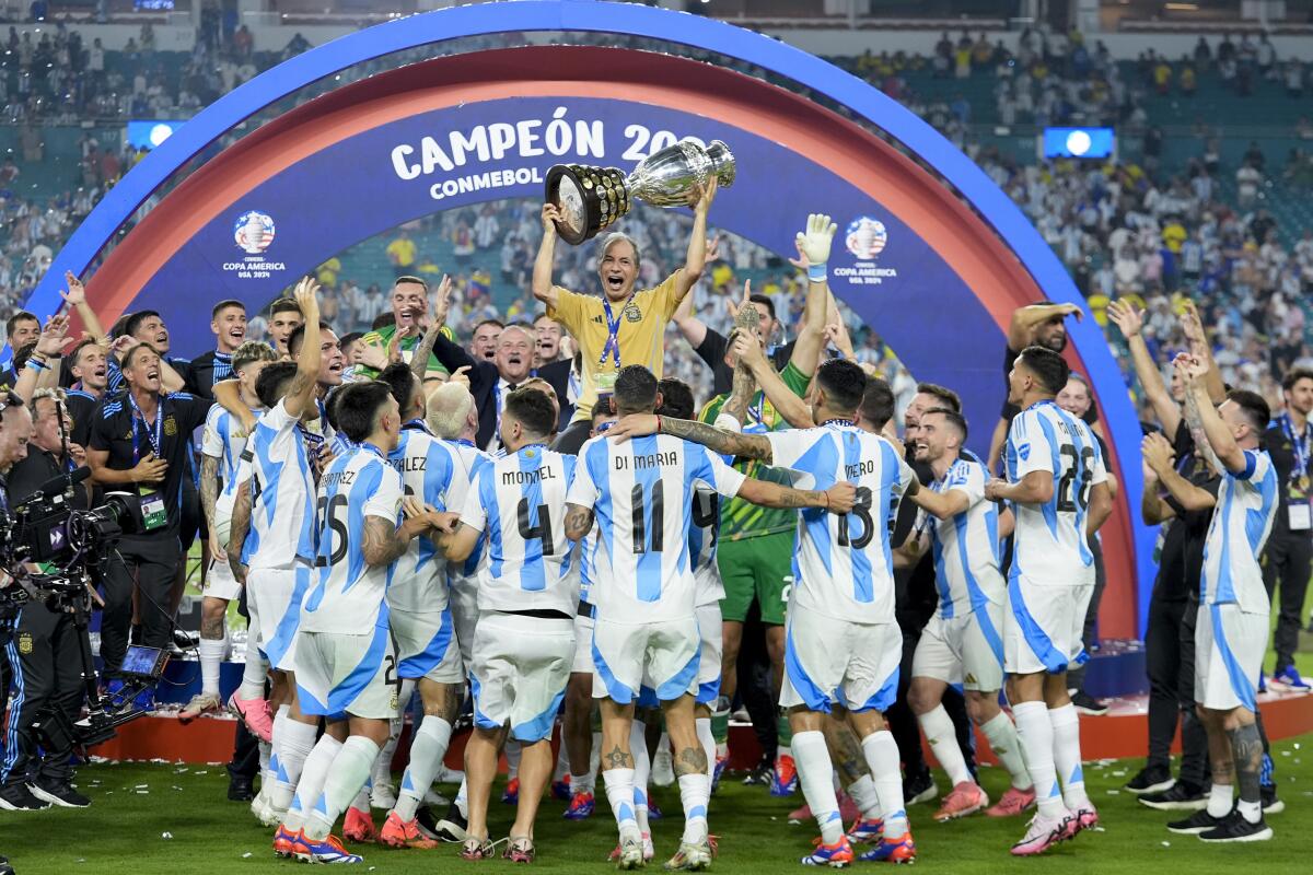 El equipador argentino Mario De Stefano sostiene el trofeo mientras celebra con los jugadores