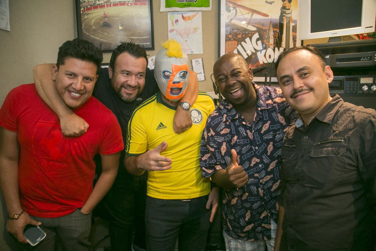 In this Thursday, July 23, 2015 photo, Radio DJs, Daniel Perez, "El Garbanzo, far left," and Oswaldo Diaz, "Erazno," third from left, pose with show producers: Raul Martinez, "El Diablito," Edwin Roman and Hessler De la Cruz, far right. El Show de Erazno y La Chokolata" radio show in Los Angeles. The program offers to help immigrants wondering if girlfriends and boyfriends, wives and husbands left behind or deported back to Mexico and Central America are being faithful. They call in, reveal their woes and then listen offline as the host calls their unsuspecting partner and offers the chance to send a free heart-shaped box of chocolate to their romantic interest. Diaz's show is broadcast by Entravision and reaches over 2 million people nationwide.