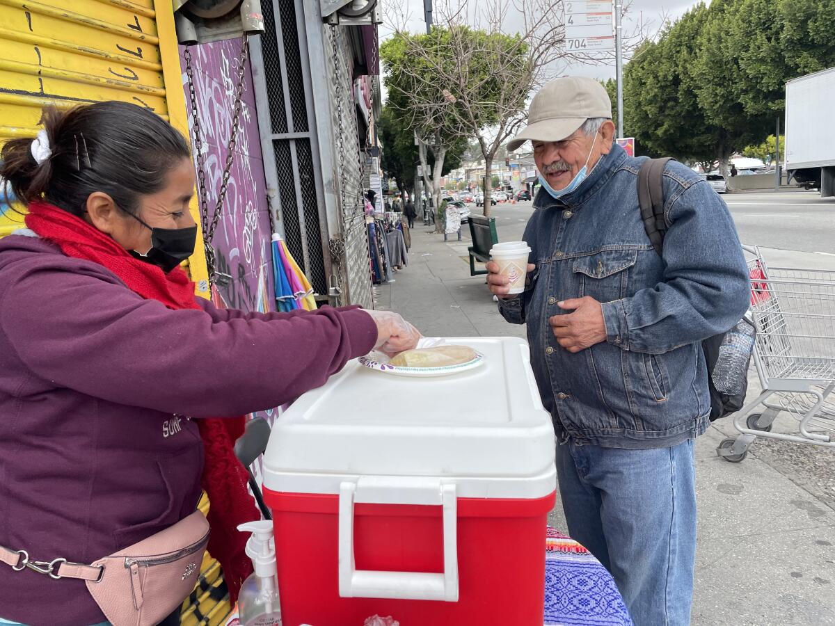 La comerciante Yolanda Ramos ofrece tamales y champurrado a los transeúntes en las inmediaciones del lago en Echo Park.