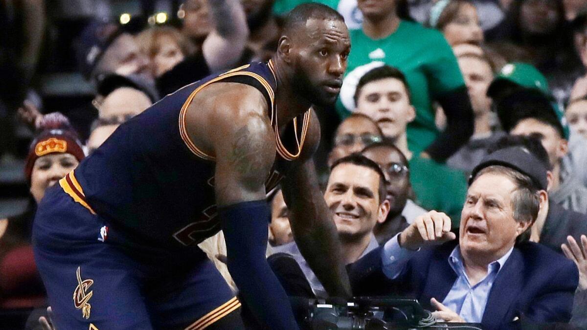 New England Patriots Coach Bill Belichick, right, braces himself as Cleveland's LeBron James comes tumbling toward him at Boston's TD Garden on March 1.