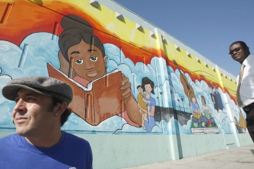 Director Mortimer Jones, right, asked artist Eduardo "Lalo" Marquez, left, to paint a mural showing the services offered by the Salvation Army Siemon Youth & Community Center.