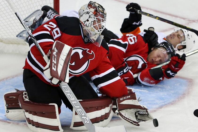 Then-New Jersey goalie Anders Lindback loses the puck as the Devils' Karl Stollery (46) and Philadelphia's Scott Laughton crash into him during an exhibition game on Sept. 26.