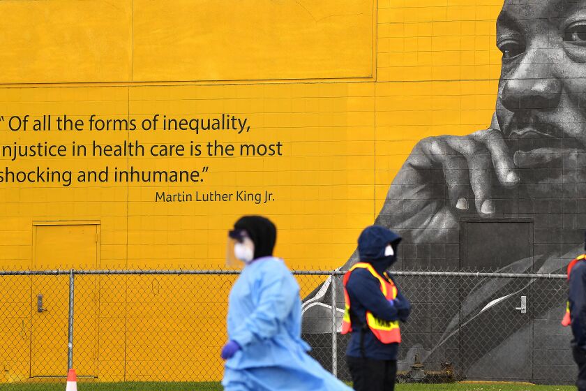 LOS ANGELES-CA-APRIL 8, 2020: A portrait and quote by Martin Luther King, Jr. overlooks a new mobile testing site for people with symptoms of the coronavirus at Charles R. Drew University of Medicine and Science in South Los Angeles on Wednesday, April 8, 2020. (Christina House / Los Angeles Times)