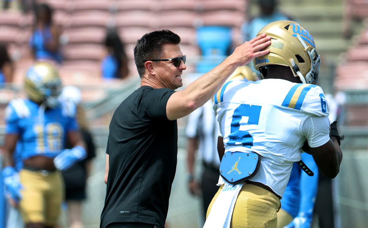 مدرب UCLA بوب تشيزني يربت على رأس لاعب الجري أنطوني وودز خلال المباراة الربيعية للفريق في استاد روز.