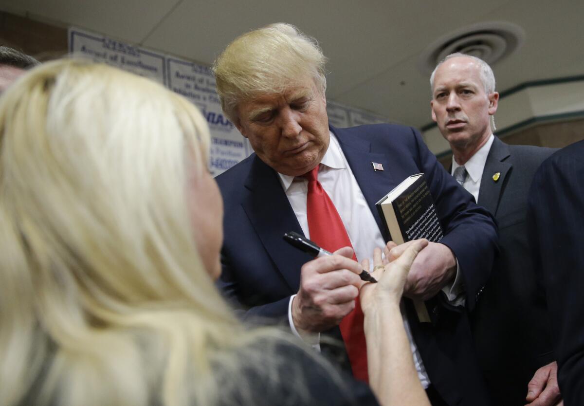 Donald Trump signs an autograph for a supporter at a caucus site in Las Vegas.