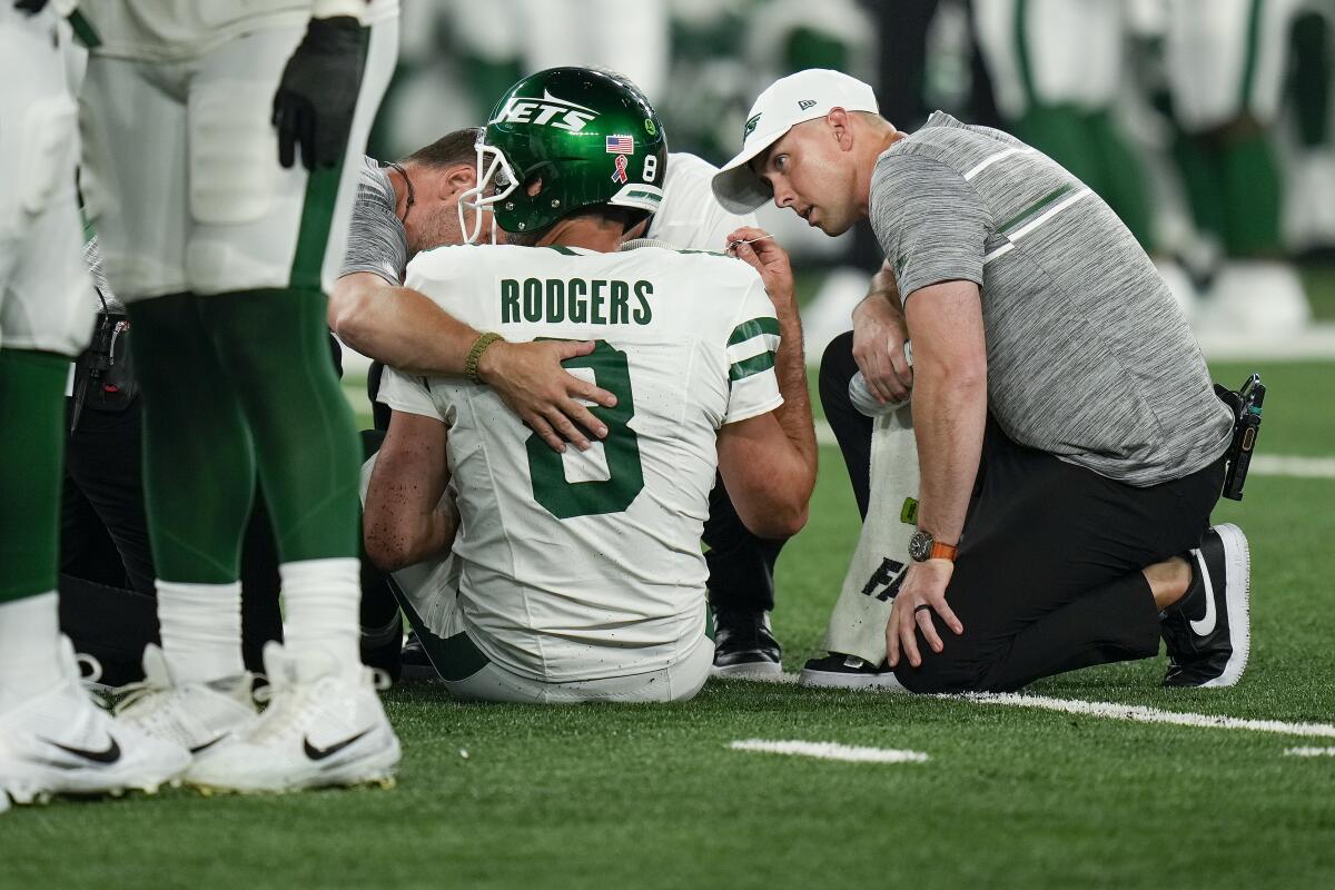New York Jets quarterback Aaron Rodgers receives attention from team trainers.