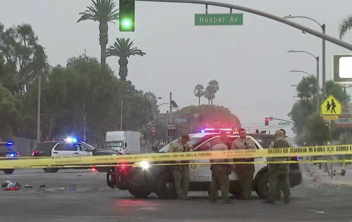 Sheriff's deputies stand in an intersection next to a patrol cruiser behind crime scene tape