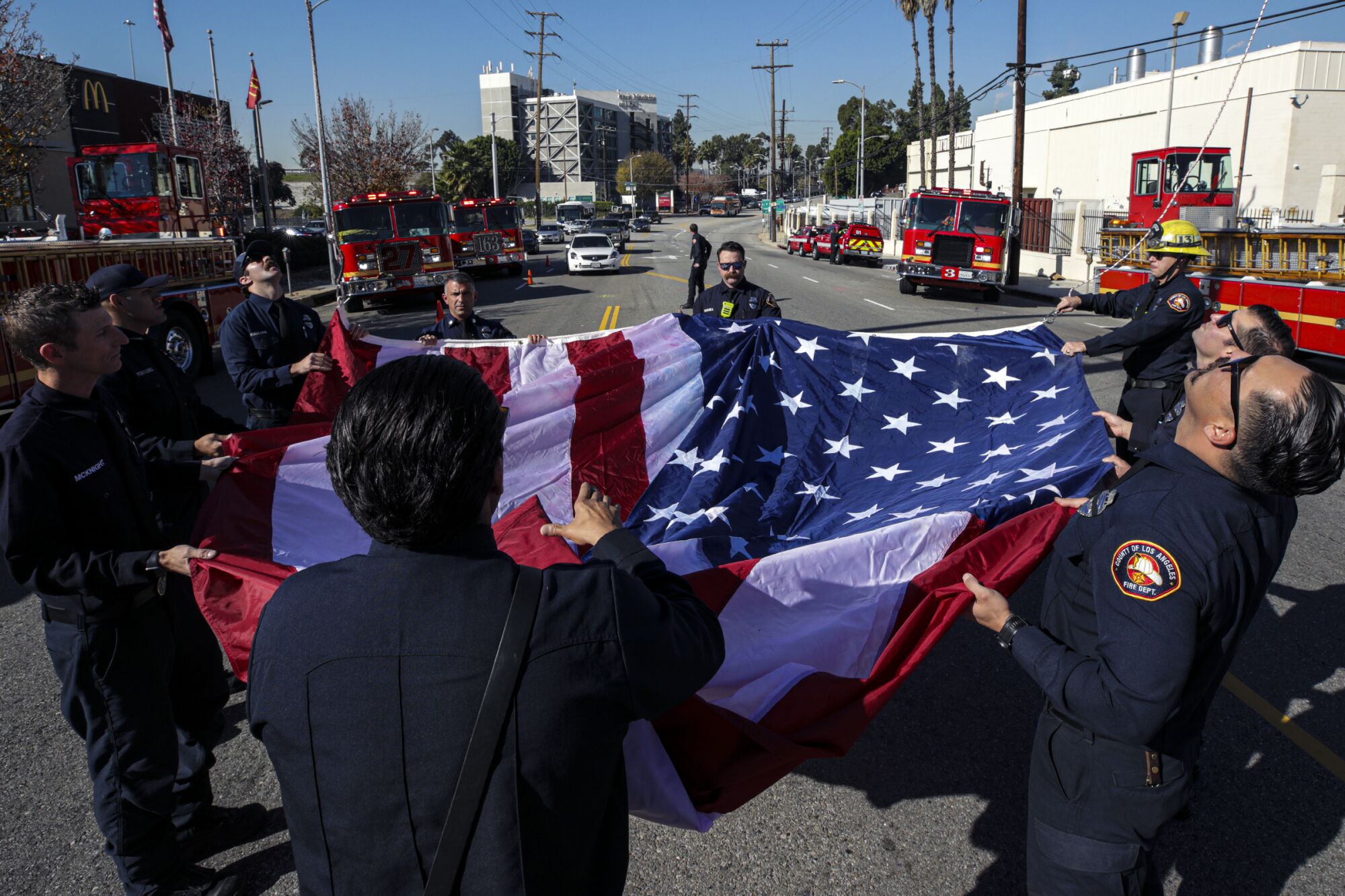 Firefighters prepare to hoist an American flag outside the coroner's office in Los Angeles