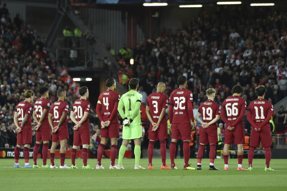 Liverpool's players stand for a minute of silence for the death of Britain's Queen Elizabeth II prior to the start of the Champions League group A soccer match between Liverpool and Ajax at Anfield stadium in Liverpool, England, Tuesday, Sept. 13, 2022. (AP Photo/Rui Vieira)