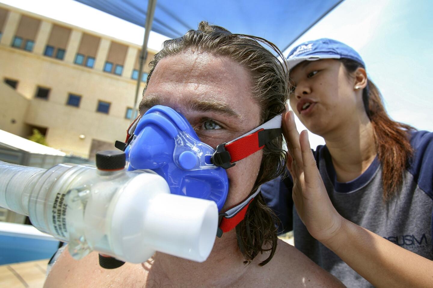 Kinesiology intern Ning Jia, 25, puts a mask, used to measure oxygen consumption, on fellow intern and student Cody Cuchna, 24, before he paddles a surfboard in a swim flume.