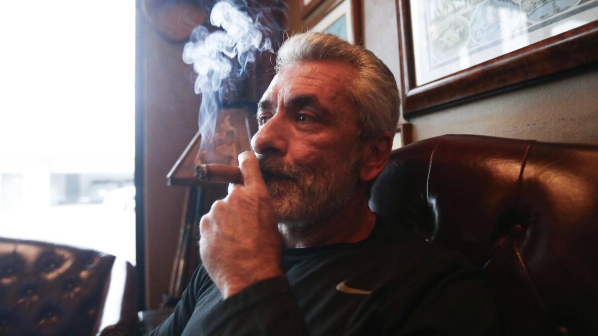 Owner Rigo Fernandez poses for photos smoking a cigar in his Buena Vista Cigar Club. Only the city's three recognized cigar lounges would be allowed to continue to sell tobacco products under a proposed law.