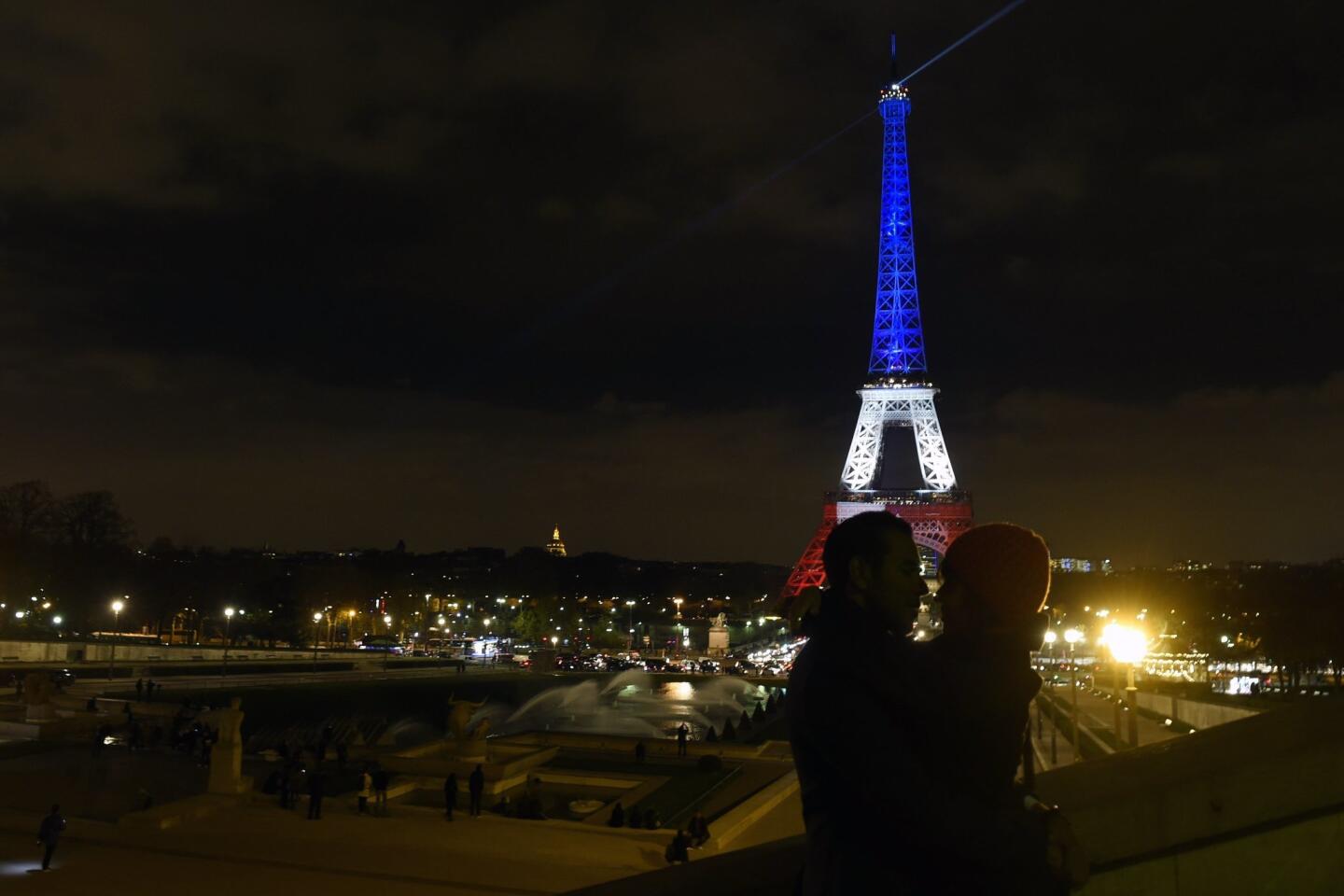 A couple embraces as the Eiffel Tower is illuminated Nov. 16, 2015, in the colors of the French flag in tribute to the victims of the terror attacks in Paris, France.