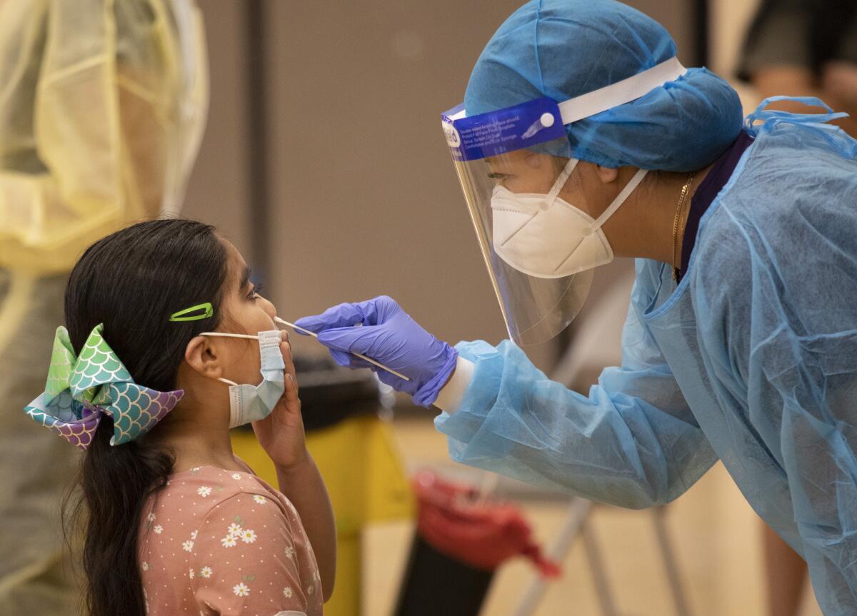 Nurse Cindy Bayasgalan swabs first-grader Alyssa Ponce's nose at a testing site at Telfair Elementary School in Pacoima.