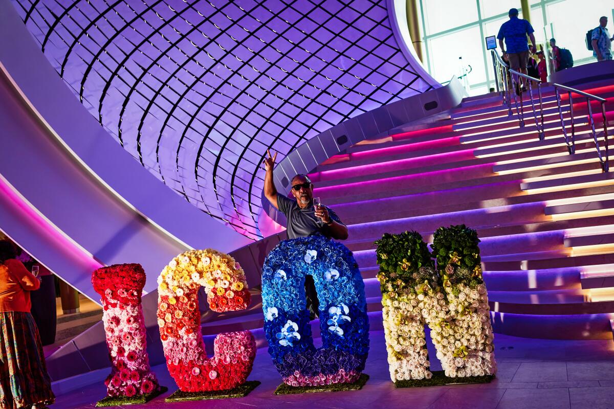 Guests pose for photos by a floral display in "Icon" letter shapes on the promenade of Royal Caribbean’s Icon of the Seas.