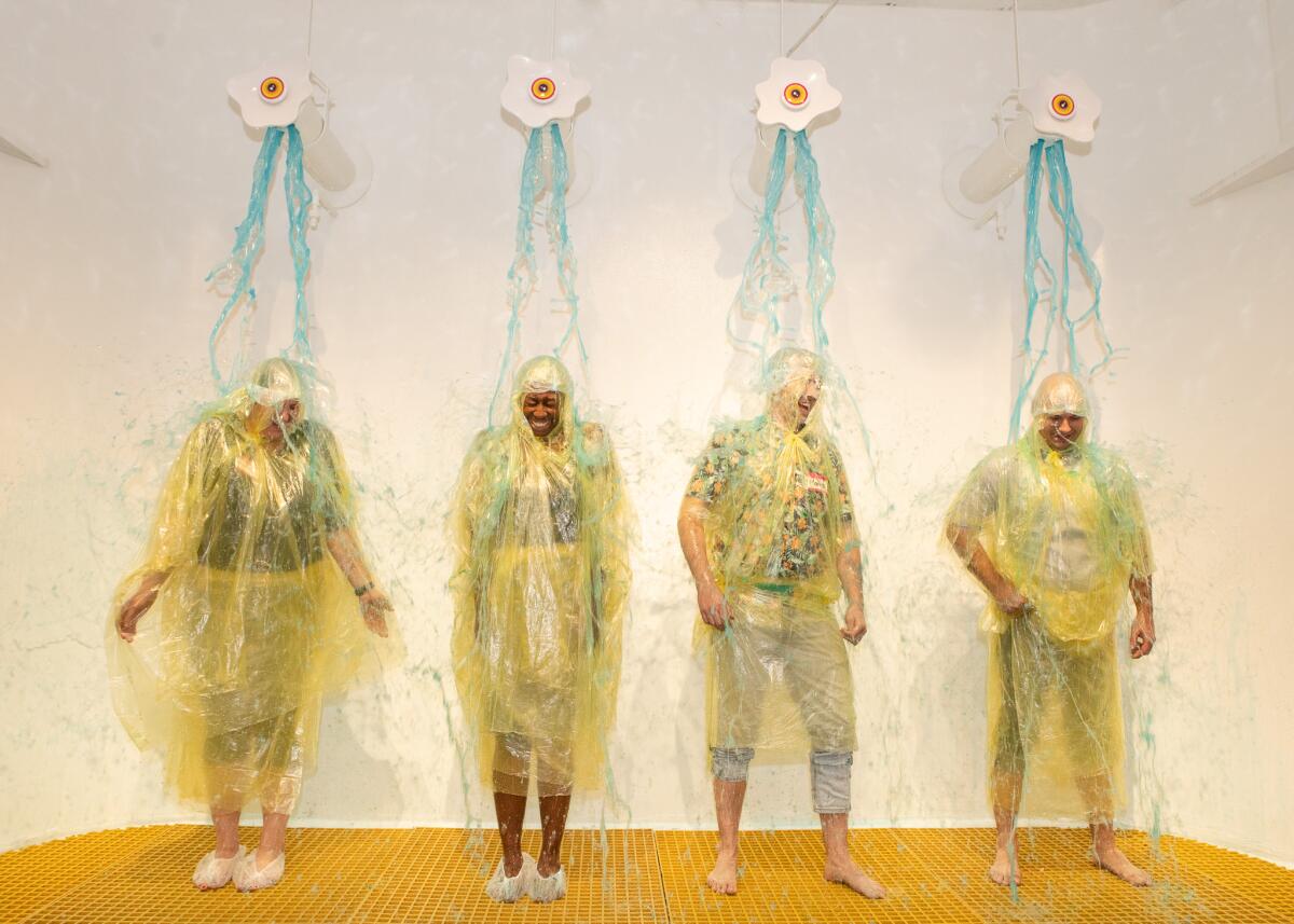Four participants in rain gear are doused in slime. 