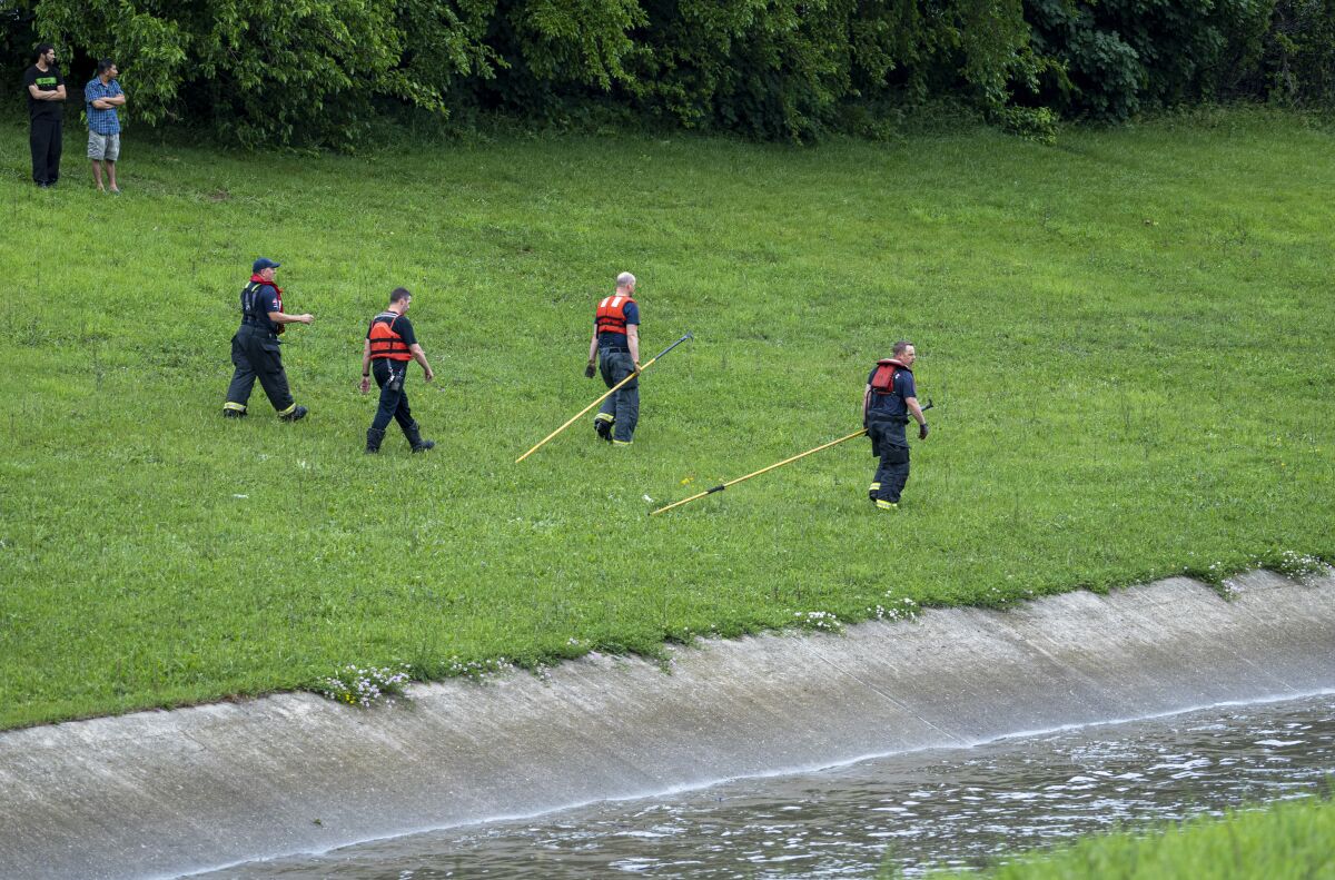 Milwaukee Fire Department Dive Rescue Team prepare a raft to enter a drainage ditch on Monday, June 13, 2022 in Milwaukee, Wis. A child and two adults were missing after they were swept away in a drainage ditch following severe thunderstorms that brought heavy rains and damaging winds to a wide swath of the Midwest and parts of the South, authorities said. (Jovanny Hernandez/Milwaukee Journal-Sentinel via AP)