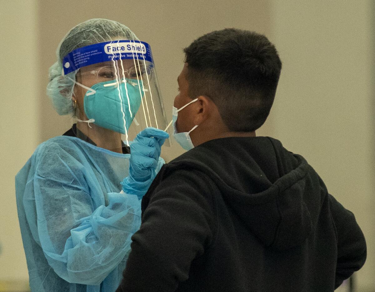 A medical professional gives a coronavirus test to a student.