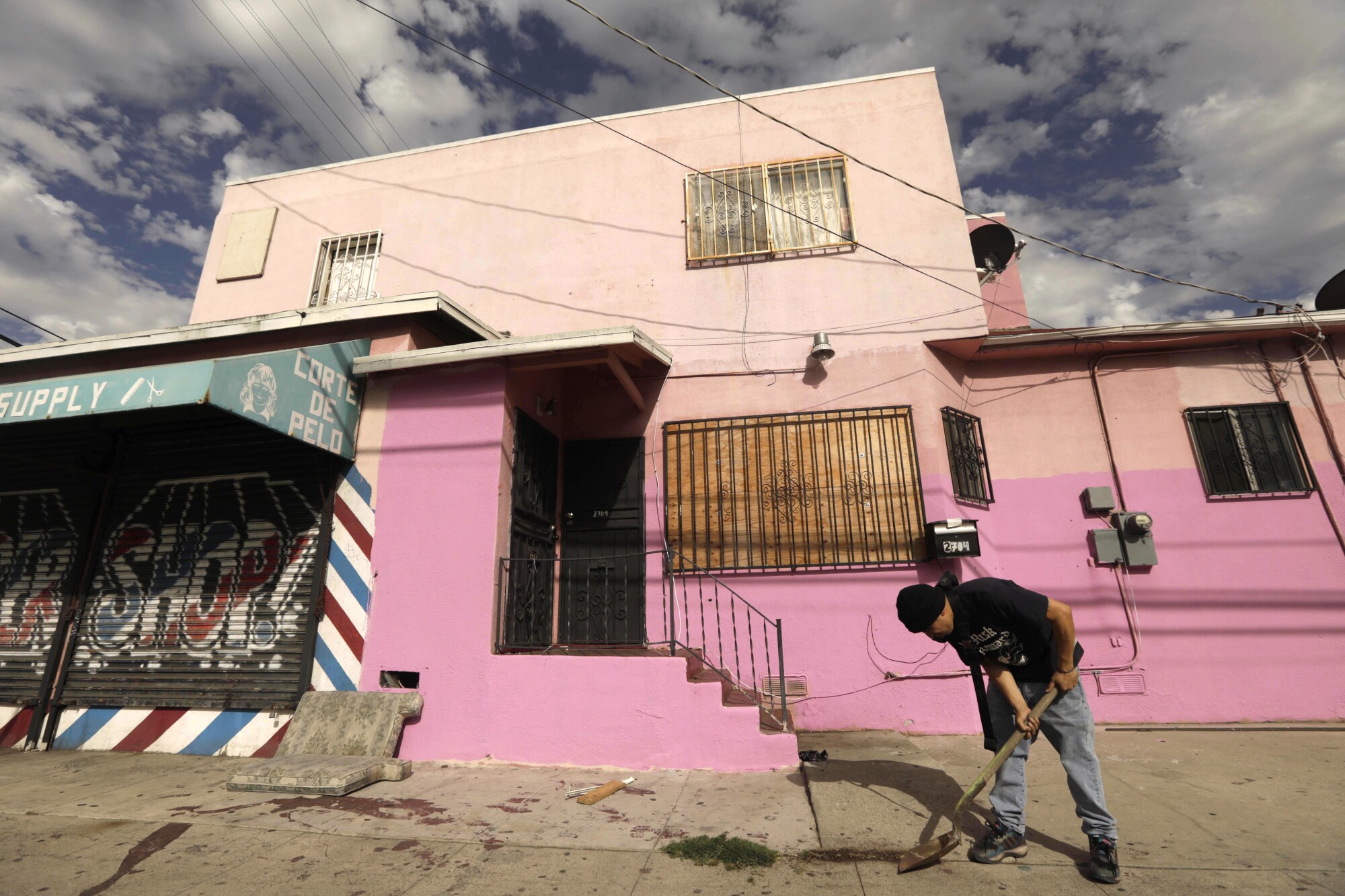 A man cleans the sidewalk in front of a bright pink building