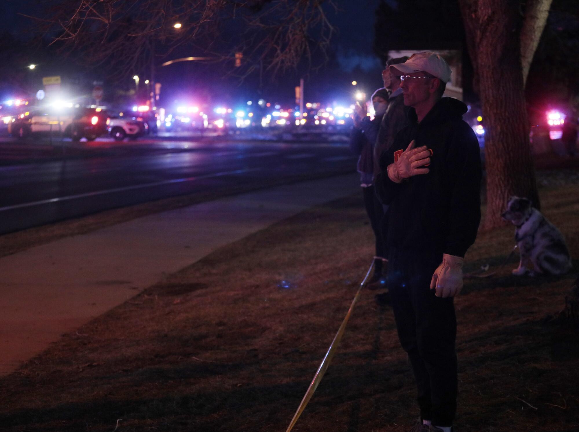 An onlooker reacts as a procession of emergency vehicles leaves a King Soopers grocery store 