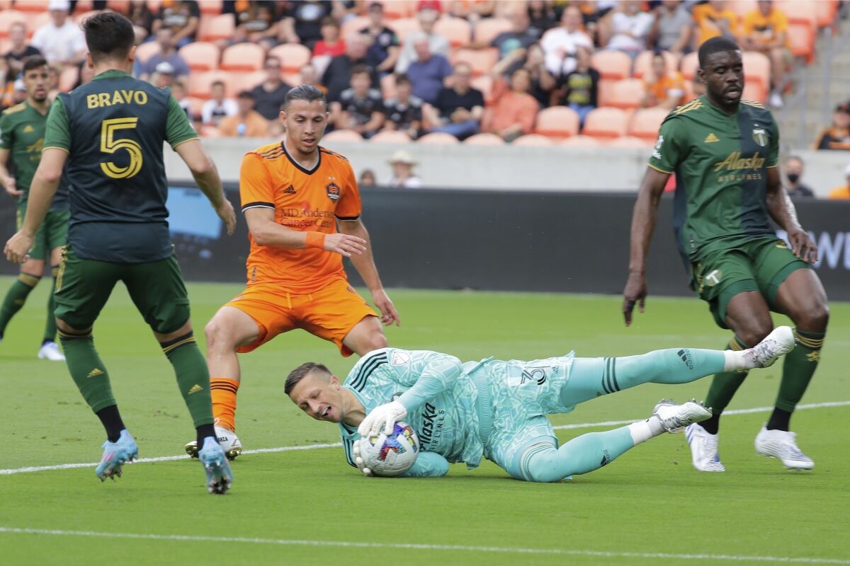 Portland Timbers goalkeeper Aljaz Ivacic, bottom, dives onto a shot on goal between, from left to right, defender Timbers' Claudio Bravo (5), Houston Dynamo forward Sebastian Ferreira (9) and Timbers defender Larrys Mabiala during the first half of an MLS soccer match Saturday, April 16, 2022, in Houston. (AP Photo/Michael Wyke)